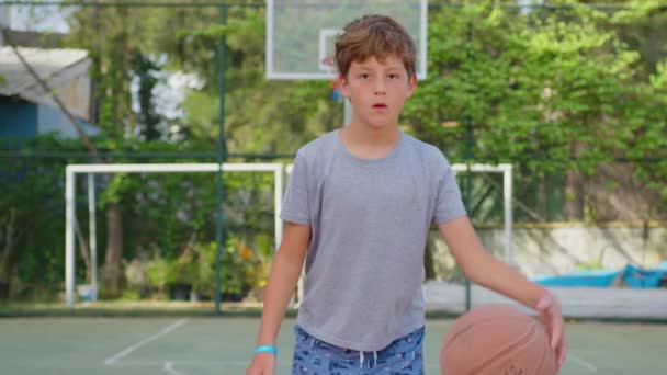 Boy practicing playing a basketball outdoor. Closeup. — Stock Video