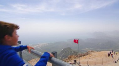 Genç adam, deniz manzaralı dağın tepesinde duruyor, Türkiye,