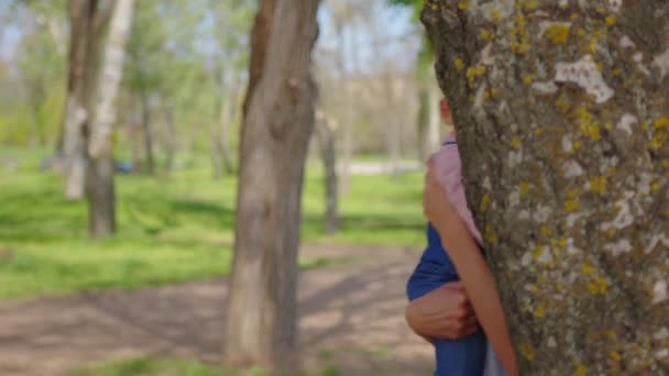 Criança bonito com a mãe jogando esconde-esconde no parque da cidade no verão. Conceito de infância e fim de semana. — Vídeo de Stock