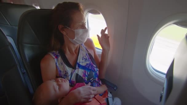 Uçakla uçma korkusu. Bebekli yolcu kadın gergin bir şekilde uçakta oturuyor.. — Stok video