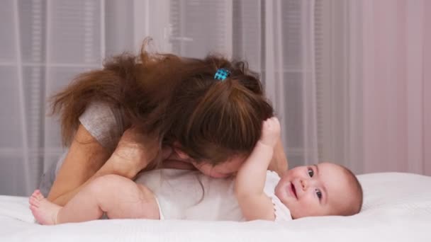 집안에서 아기를 돌보고 있는 사랑많은 어머니가 아기를 장난감으로 즐겁게 돌보고 있는 어머니에게 부드럽게 근접 한 어머니는 갓 태어난 아기를 건강하게 돌보아 주고 있다. — 비디오