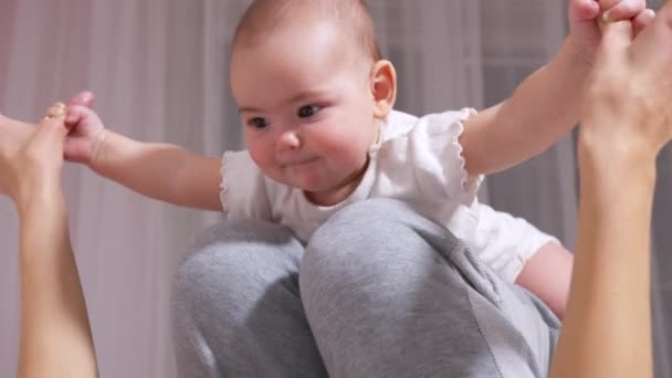 Gelukkig gezond jong volwassen moeder tillen schattig kind dochter up spelen vliegtuig op bed. Loving mam doet yoga gymnastiek oefening met grappige schattige baby in gezellige slaapkamer. — Stockvideo