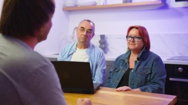 Mutlu orta yaşlı aile çifti erkek emlakçı, mali danışman ya da avukatla tanışıyor sözleşme detaylarını tartışıyor, ofiste anlaşma yapıyor..