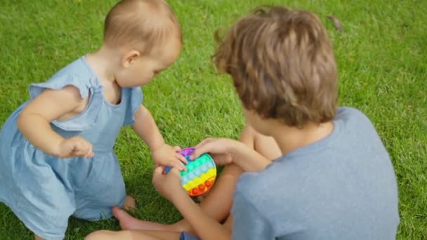 Kinder spielen Pop it Spielzeug einfache Grübchen auf der Straße stehen. — Stockvideo