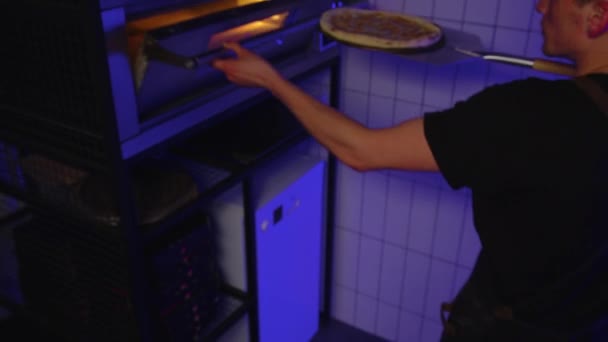 Primer plano del chef poniendo pizza para hornear en el horno en la cocina del restaurante. — Vídeos de Stock