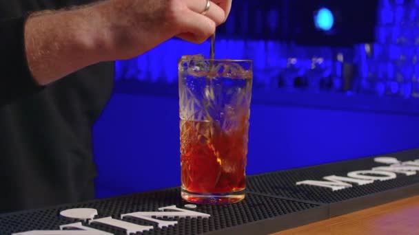 Barista professionista che crea un cocktail drink. Barman esperto versando bevande alcoliche, retroilluminazione blu. — Video Stock