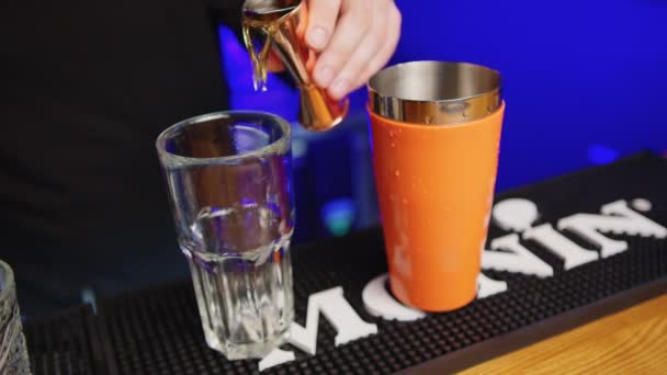 Professional bartender creating a cocktail drink. Experienced barman pouring alcohol beverage in glass before serving - food and drink concept close up. — Stock Video