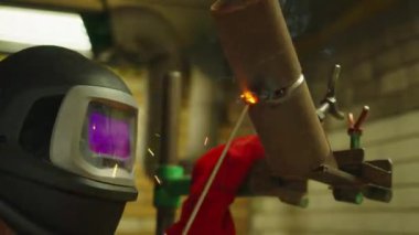 Koruyucu maskeli demirci metal ve demirle çalışıyor kaynak makinesi, parlak kıvılcımlar ve flaşlar kullanıyor..