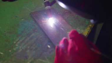 Fabrikada çelik kaynak makinesiyle çalışan metal kaynakçı güvenlik ekipmanı takıyor. El becerisi iş gücü kavramına göre metal imalatı ve inşaat bakım hizmeti.