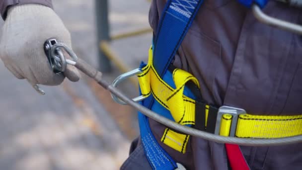 Industriell klättrare sätter på sig utrustning för höghöjdsarbete. På karbinhakar med klätterbälte. — Stockvideo
