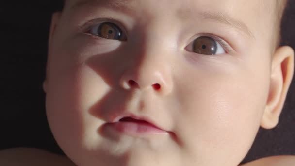 De blik van de baby in de camera van dichtbij bekeken. Een schattige kleine baby kijkt in de camera. Concept van zorg voor kinderen, ouderlijke liefde. — Stockvideo