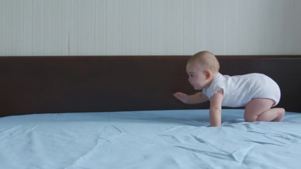Ευτυχισμένο μωρό σέρνεται στο κρεβάτι. Το βρέφος παίζει με την οικογένεια στο σπίτι και μαθαίνει πώς να σέρνεται γρήγορα κατά τη διάρκεια των παιχνιδιών. — Αρχείο Βίντεο