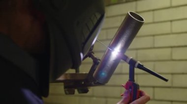 Fabrikada çelik kaynak makinesiyle çalışan metal kaynakçı güvenlik ekipmanı takıyor. El becerisi iş gücü kavramına göre metal imalatı ve inşaat bakım hizmeti.