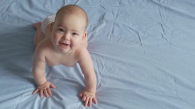 Yeni doğmuş beyaz bir bebek komik bir şekilde gülümsüyor. Neşeli ve enerjik bir çocuğun portresi.