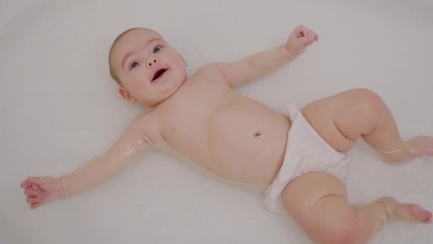 Baby Close Up Playing in Bath. Top view of funny newborn baby swimming during bathing. — Stockvideo