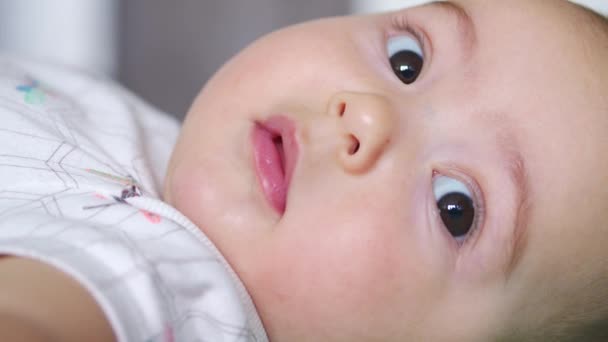 La mirada del bebé en la cámara de cerca disparó. Un lindo bebé está mirando a la cámara. Concepto de cuidado de los niños, amor de los padres. — Vídeos de Stock