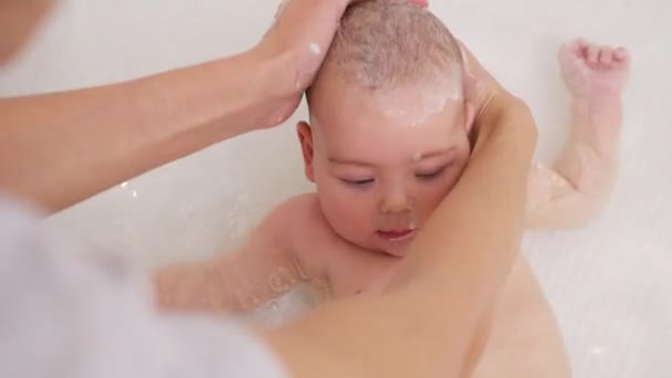 Очаровательный ребенок, принимающий ванну с матерью, моющей ему голову. — стоковое видео