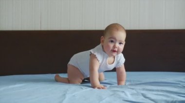 Mutlu bebek yatakta emekliyor. Bebek evde ailesiyle oynuyor ve yakalama oyunlarında süratle emeklemeyi öğreniyor..