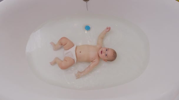 Baby Close Up Playing in Bath. Top view of funny newborn baby swimming during bathing. — Stockvideo