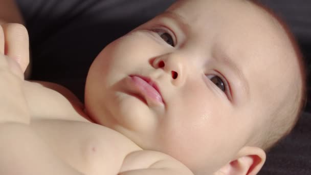 Το βλέμμα του μωρού στην κάμερα από κοντά. Ένα χαριτωμένο μωράκι κοιτάει στην κάμερα. Έννοια της φροντίδας των παιδιών, γονική αγάπη. — Αρχείο Βίντεο