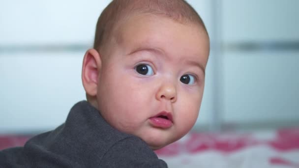 La mirada del bebé en la cámara de cerca disparó. Un lindo bebé está mirando a la cámara. Concepto de cuidado de los niños, amor de los padres. — Vídeos de Stock