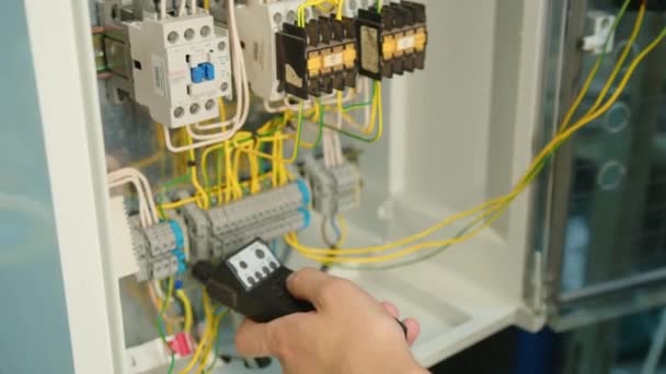 Een close-up. Elektriciens handen testen stroom elektrisch in het bedieningspaneel. Elektricien ingenieur werk tester meetspanning en stroom van de macht elektrische lijn in electische kast controle. — Stockvideo