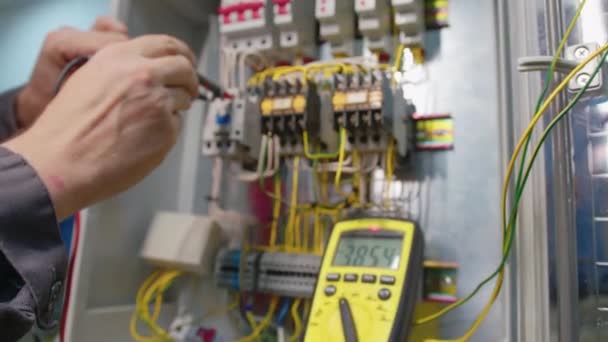 Gli elettricisti testano la corrente elettrica nel pannello di controllo. Tester di lavoro dell'ingegnere elettrico che misura tensione e corrente della linea elettrica di alimentazione nel controllo elettrico del gabinetto. — Video Stock