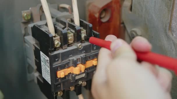 Een close-up. Elektriciens handen testen stroom elektrisch in het bedieningspaneel. Elektricien ingenieur werk tester meetspanning en stroom van de macht elektrische lijn in electische kast controle. — Stockvideo