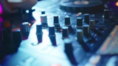 Kapatın. Disko kulübünde dans müziği karıştırmak için DJ ses kontrol konsolu. Eller düğmelere basıyor, karıştırma güvertesinde elektronik müzik çalıyor, gece kulübü dans partisinde renk aydınlatması..