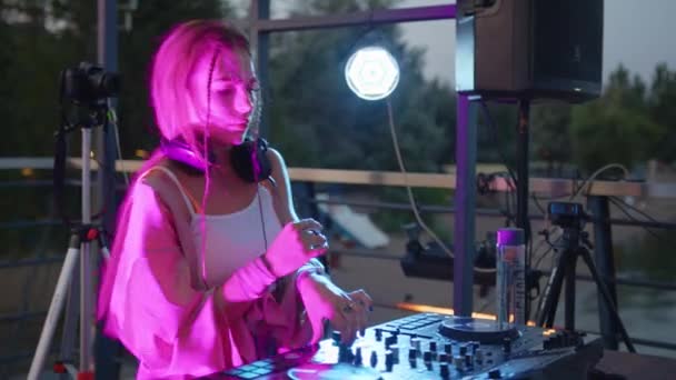 Cool DJ arbetar i en nattklubb, står vid skivspelare, skapa en dans musik set - nattliv koncept 4k film. — Stockvideo