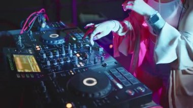 DJ eller disko kulübünde müziği karıştırmak için ses konsolunu kontrol eder. Ağır çekimde kapat. Parmaklar düğmelere basar, güvertede elektronik müzik çalar. Gece kulübü dans partisinde renk ışıkları görünür..