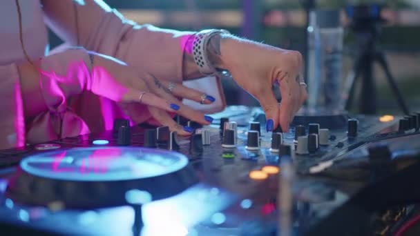 DJ mãos controlar o console de som para misturar música no clube de discoteca. Feche em câmara lenta. Fingers toque botões deslizantes, tocando música eletrônica no convés. Cor luzes mostram na festa de dança da discoteca. — Vídeo de Stock