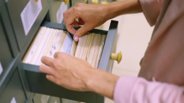Uma mulher mão procurando cartões no catálogo velho cartão de madeira. Um catálogo de bibliotecas vintage, para uma busca conveniente e rápida por um livro. Procure informações no arquivo de cartão na biblioteca. — Vídeo de Stock