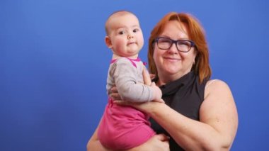 Torununu kucağında tutan son sınıf öğrencisi genç ve yaşlı insanları bir arada tutuyor. Mavi arka planda büyükannesi olan bir bebek..