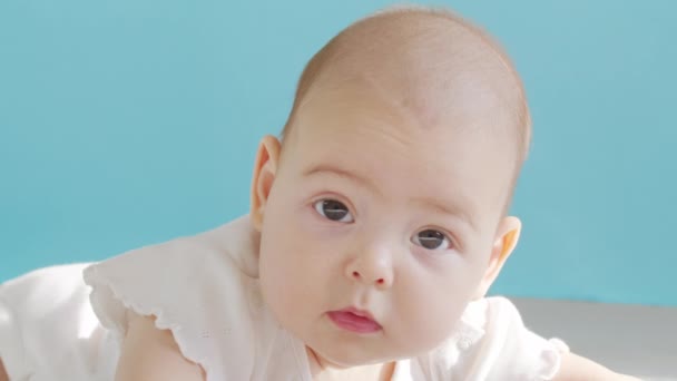 クローズアップの肖像画は、幼児の女の子。ベッドの上には白人の少女の顔が横たわっていた。赤ちゃん6ヶ月カメラを見て. — ストック動画