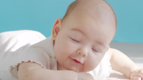 Mooie glimlach Baby: Een prachtige kleine baby ligt op het bed en glimlacht naar de camera met een mooie zachte focus achtergrond. — Stockvideo