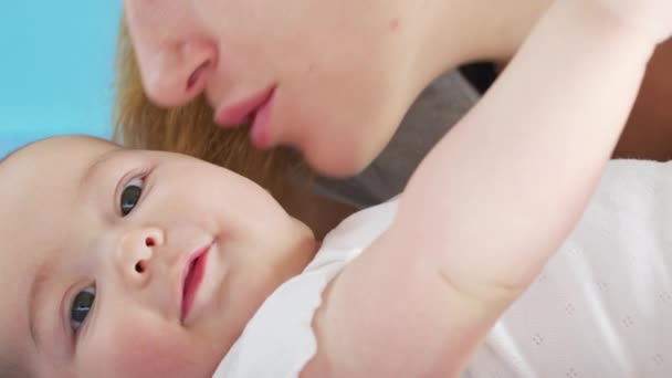 Η τρυφερή στοργική μητέρα φιλάει το δέσιμο με την χαριτωμένη κορούλα ξαπλωμένη στο κρεβάτι. Χαρούμενη στοργική μαμά και αστείο αξιολάτρευτο μωρό παιδί γιος παίζει διασκεδάζοντας στην κρεβατοκάμαρα. — Αρχείο Βίντεο