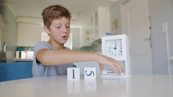 Biały zegar na stole przekręca się przez miesiąc, odwracając dni i datę. Chłopiec na zegarze wyznacza datę pierwszego stycznia.. — Wideo stockowe