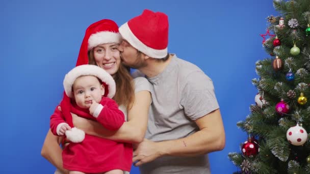 Νεαρή ευτυχισμένη οικογένεια κοντά στο χριστουγεννιάτικο δέντρο χαμογελώντας χαιρετούν κάνοντας Selfie ή βίντεο μήνυμα έννοια των οικογενειακών διακοπών και της Πρωτοχρονιάς. — Αρχείο Βίντεο