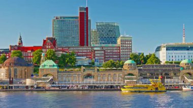 View of Hamburgs waterfront and citycenter and ships and boats passing along the Elbe River at sunset in Hamburg, Germany.