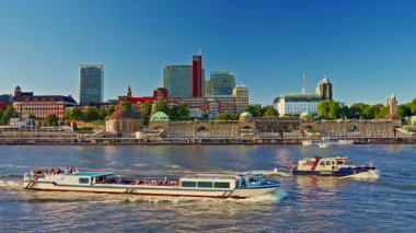 Hamburg, Almanya - 08.08.2025: Hamburgs rıhtım ve şehir merkezi ve Elbe Nehri 'nden gün batımında geçen gemi ve teknelerin görüntüsü.