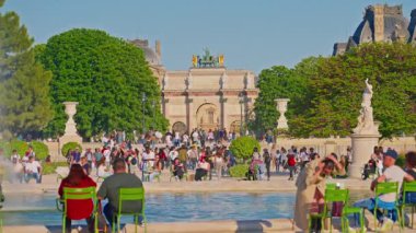 Tuileries Garden, Paris, Fransa, 30.05.2025. İnsanlar parkta yürüyor ve çeşmenin yanındaki sandalyelerde oturuyorlar..
