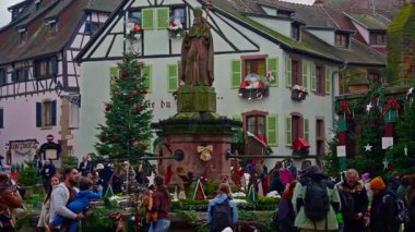 Eguisheim, Fransa - 3.12.2025: Noel için dekore edilmiş küçük, güzel bir köy. İnsanlar güzel dekore edilmiş Fransız köyü Eguisheim sokaklarında geziniyor..