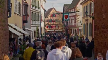 Eguisheim, Fransa - 3.12.2025: Noel için dekore edilmiş küçük, güzel bir köy. İnsanlar güzel dekore edilmiş Fransız köyü Eguisheim sokaklarında geziniyor..