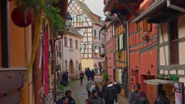Eguisheim, Fransa - 3.12.2025: Noel için dekore edilmiş küçük, güzel bir köy. İnsanlar güzel dekore edilmiş Fransız köyü Eguisheim sokaklarında geziniyor..