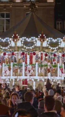 Strasbourg, Fransa - 1 Aralık 2025: Strazburg 'da Noel' in kalbinde Noel pazarı. Noel için dekore edilmiş geleneksel bir Fransız atlıkarınca. Fransa. Dikey video.