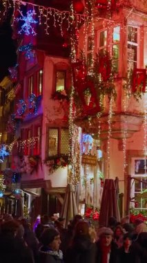Strazburg, Fransa - 01.12.2025: Strazburg sokakları Noel için süslenmiş ve akşamları aydınlatılmıştır. Evin güzel dekore edilmiş dış görünüşü. Dikey video.