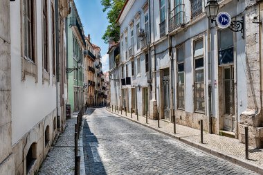 Portekiz, Lizbon 'un Bairro Alto bölgesinde gün ortasında boş bir cadde aydınlık ve gölgelerle doludur..