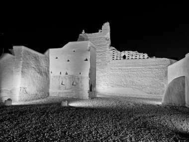 Suudi Arabistan 'ın Riyad kenti yakınlarındaki Diriyah şehrinin eski kale duvarlarının küçük bir kısmı geceleri aydınlanıyor. Siyah ve beyaz..