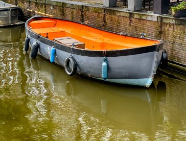 Hollanda turuncu boyalı küçük bir tekne Amsterdam 'daki kanallardan birine demirlemiş..